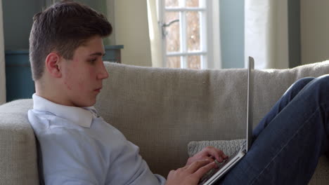 Teenager-Sitzt-Zu-Hause-Auf-Dem-Sofa-Und-Benutzt-Laptop,-Aufgenommen-Auf-R3D