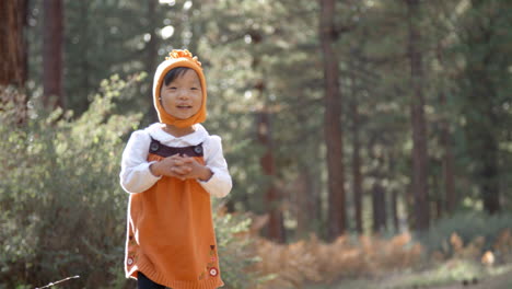 Asian-toddler-girl-walking-alone-in-a-forest,-front-view