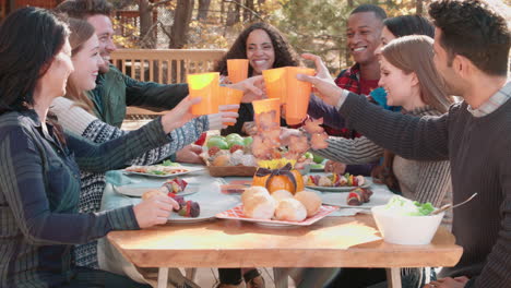Group-of-happy-friends-at-a-table-outdoors-making-a-toast