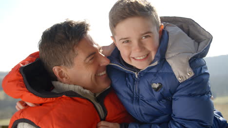 Father-holding-son-outdoors,-both-in-warm-clothing,-close-up