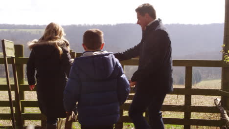 Family-with-dog-walking-through-rural-gate,-back-view,-shot-on-R3D