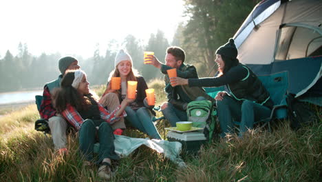 Group-of-friends-on-a-camping-trip-sitting-outside-a-tent