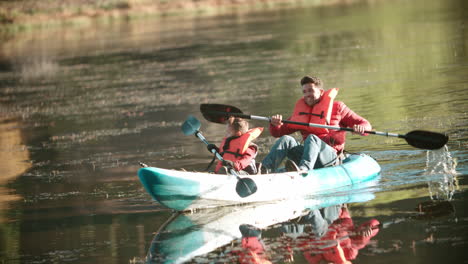 Padre-E-Hijo-Navegando-En-Kayak-En-Un-Lago-Durante-Un-Viaje-De-Campamento