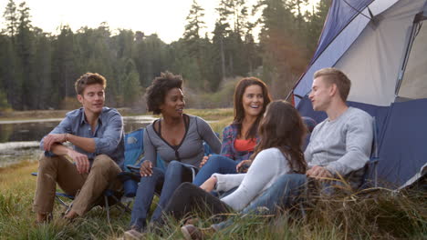 Friends-on-a-camping-trip-relaxing-by-their-tent-near-a-lake