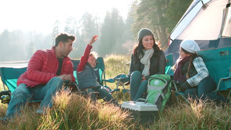Parents-with-two-kids-on-a-camping-trip-sitting-outside-tent