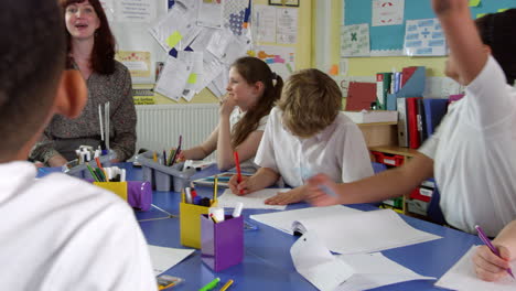 Pupils-And-Teacher-Sitting-At-Table-In-Classroom-Shot-On-R3D