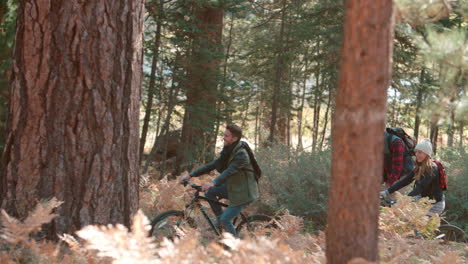 Friends-riding-bikes-in-forest,-side-view,-right-to-left-pan