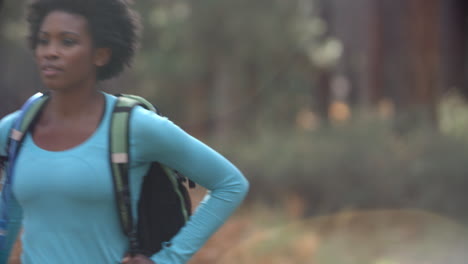 African-American-woman-running-in-a-forest-with-a-backpack