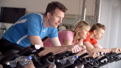 Side-view-of-a-spinning-class-on-exercise-bikes-at-a-gym