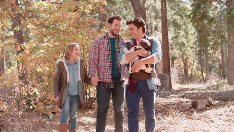 Male-parents-in-forest-with-baby-and-daughter-walk-to-camera