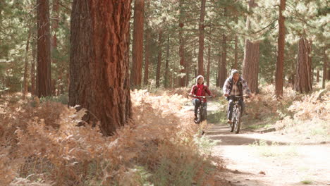 Senior-black-couple-cycling-towards-camera-on-a-forest-trail