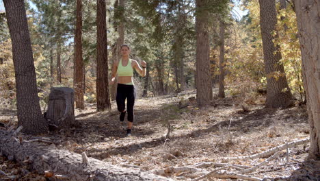 Low-angle-shot-of-young-woman-running-in-a-forest