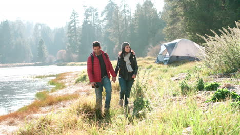 Couple-holding-hands-walking-near-lake-on-a-camping-trip