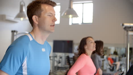 Man-and-two-young-women-running-on-treadmills-at-a-gym