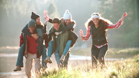 Five-friends-have-fun-piggybacking-by-a-rural-lake