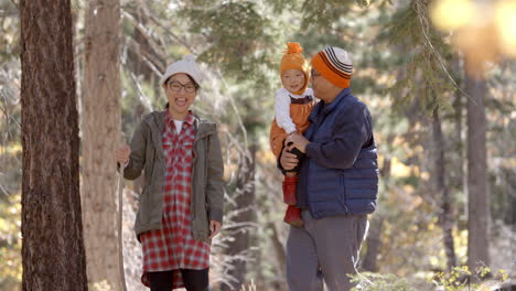 Pregnant-woman,-husband-and-young-daughter-hike-in-a-forest