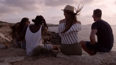 Group-Of-Friends-Sit-On-Cliff-Watching-Sunset-Shot-On-R3D