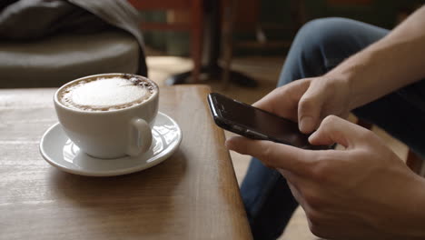 Young-man-in-cafe-messaging-with-smartphone,-close-up-detail