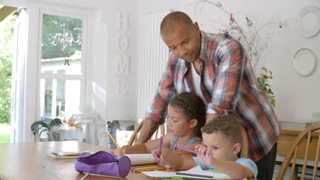 Father-Helping-Children-With-Homework-At-Table