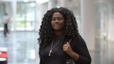 Black-female-university-student-walking-into-focus-in-lobby