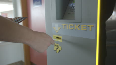Young-man-inserts-car-park-ticket-into-ticket-machine,-detail