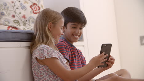 Two-Children-Sitting-On-Floor-And-Playing-With-Smartphone