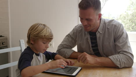 Father-and-son-using-tablet-computer-at-the-kitchen-table,-shot-on-R3D