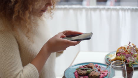Food-Blogger-Taking-Picture-Of-Meal-In-Restaurant-On-Mobile
