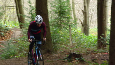 Young-man-cross-country-cycling-in-forest,-front-view,-shot-on-R3D