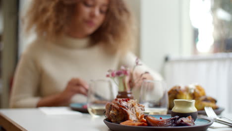 Close-Up-Of-Food-As-Woman-Enjoys-Meal-In-Restaurant