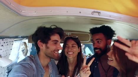 Friends-in-the-back-of-a-camper-van-on-a-trip-taking-selfie