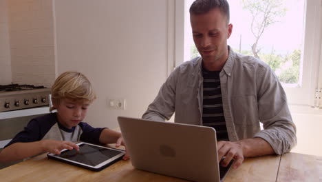 Father-and-son-using-computers-at-the-kitchen-table,-shot-on-R3D