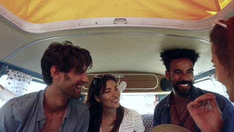 Four-friends-on-a-road-trip-talk-in-the-back-of-a-camper-van