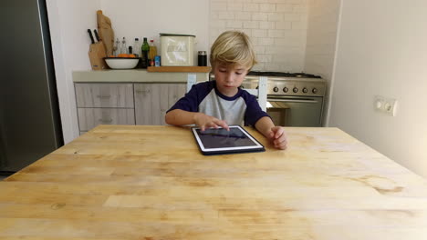Young-boy-using-tablet-computer-in-kitchen,-zoom