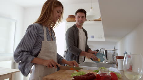 Young-adult-couple-talking-as-they-prepare-food-and-wash-up,-shot-on-R3D
