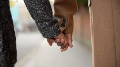 Close-Up-Of-Couple-Holding-Hands-Walking-Along-City-Street