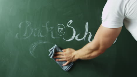 Back-to-school,-man-cleaning-text-from-chalkboard,-close-up,-shot-on-R3D
