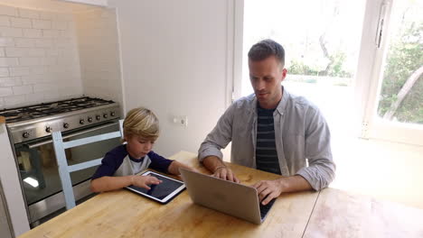 Vater-Und-Sohn-Benutzen-Computer-Am-Küchentisch