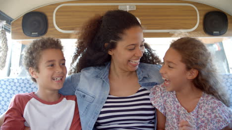Mother-and-young-children-sitting-in-the-back-of-camper-van