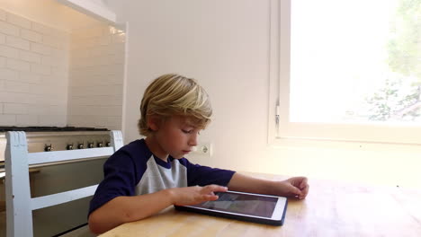 Handheld-arc-shot-of-boy-using-tablet-computer-in-kitchen