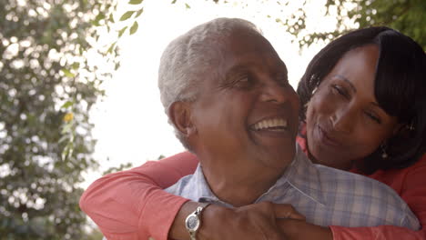 Senior-black-couple-piggyback-in-garden,-close-up