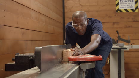 Male-Carpenter-Using-Plane-In-Woodworking-Woodshop