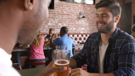 Two-Male-Friends-Eating-Out-In-Sports-Bar
