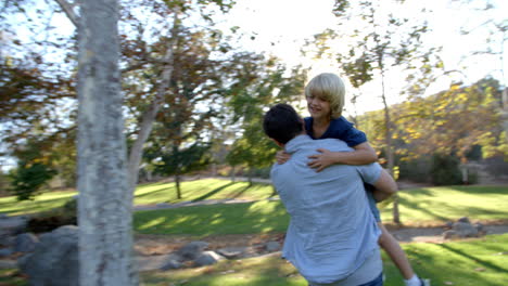 Father-Carries-Son-As-They-Have-Fun-In-Park-Together