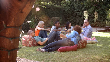 Group-Of-Mature-Friends-Enjoying-Picnic-In-Backyard-Together