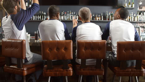 Rear-View-Of-Male-Friends-Watching-Game-In-Sports-Bar