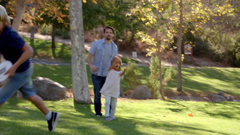 Vater-Und-Kinder-Werfen-Gemeinsam-Frisbee-Im-Park