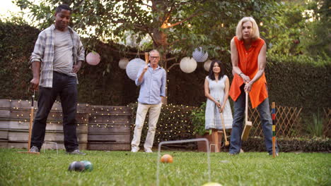 Group-Of-Mature-Friends-Playing-Croquet-In-Backyard-Together