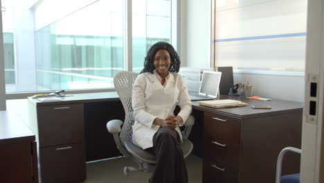 Portrait-Of-Female-Doctor-Working-At-Desk-In-Office