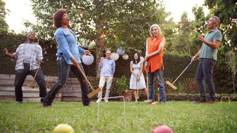 Group-Of-Mature-Friends-Playing-Croquet-In-Backyard-Together